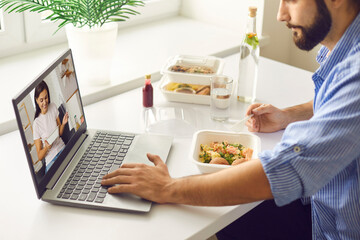 Young man having virtual lunch with wife or girlfriend during break at work or in home office