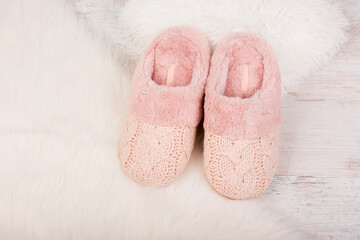 Pair of warm female slippers on white furry carpet