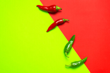 Hot red and green fresh chili peppers on red green background flat lay top view. Seasoning for dish, spicy spices for cooking, cayenne pepper, food. Creative layout, chili pattern