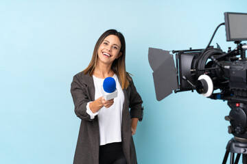 Reporter woman holding a microphone and reporting news over isolated blue background