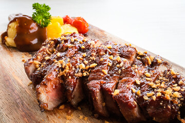 Grilled pork steak with tomato, pineapple and mashed potato on wood plate close-up.