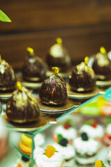 Chocolate little cake on a holiday table with desserts.  Candy bar. Delicious holiday reception on dessert table. Dessert in chocolate glaze.