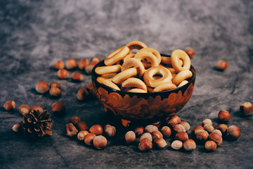 Russian bagels and hazelnuts in nutshell in Khokhloma plate on the stone table.