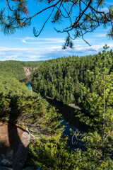 A view looking out over the river and lush green forest of the Barron Canyon in eastern Algonquin Park, Ontario on a beautiful late summer day with a blue sky.