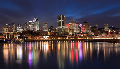 Fototapeta na wymiar Montreal skyline illuminated at night with nice reflections in Saint Lawrence River, Quebec, Canada