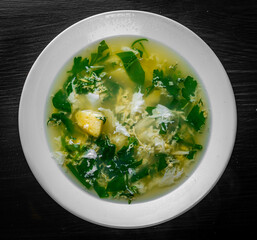 Green Sorrel soup in white plate on black wooden table background