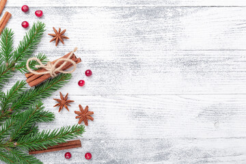 Christmas background with fir tree, spice and red cranberry on wooden table. Top view Copy space
