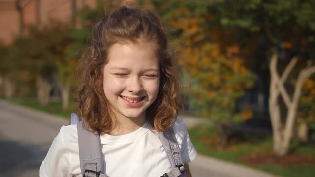 Portrait of happy caucasian girl with school bag standing outdoor