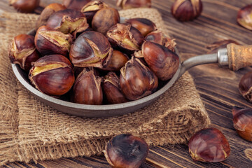Chestnuts in a pan on a wooden background. Rustic style