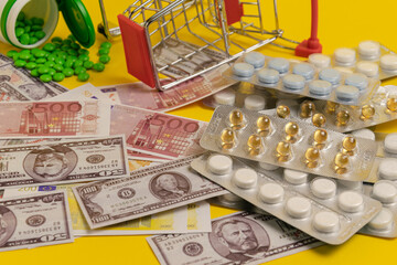 Euro and dollar banknotes lie together with medicines on a yellow background