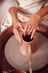 Close Up Of Female Potter Shaping Clay For Pot On Pottery Wheel In Ceramics Studio