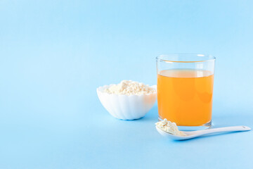Spoon of protein or collagen and orange juice. Food supplement concept. Natural beauty and health supplement. Plant based collagen. Copy space.