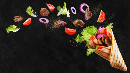 Doner kebab or shawarma with ingredients floating in the air : beef meat, lettuce, onion, tomatos, spice. Black background. Copy space. - obrazy, fototapety, plakaty