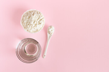 Collagen powder and a glass of water on a pink background. Healthy lifestyle. Natural beauty and health supplement. Copy space, flat lay