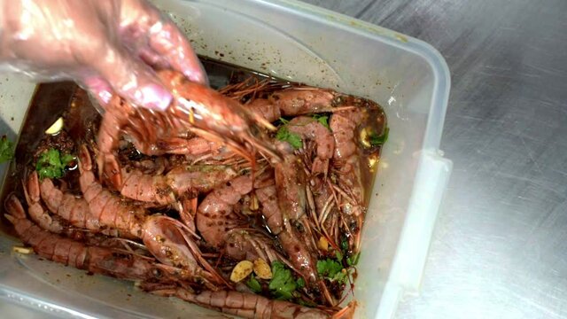 Shrimps with soy sause, garlic and parsley in box. Chef marinates shrimps. HD