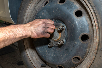 The car mechanic inserts the bolts to screw the cars steel rim to the hub.