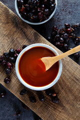 Homemade rosehip marmalade in ceramic bowl with dried rose hip fruits on wooden board.