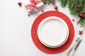 Christmas festive table setting with white and red holiday decorations on white table.
