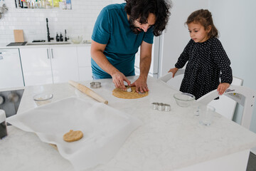 dad and daughter using cookie cutter to cut out sugar cookies