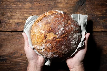 Gordijnen Bakkershanden die vers gebakken brood vasthouden en presenteren © Alexander Raths
