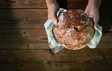 Zelfklevend Fotobehang Bakkershanden die vers gebakken brood vasthouden en presenteren © Alexander Raths