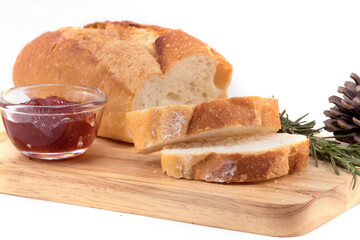 Sliced french bread and strawberry jam on wooden plate on white background.