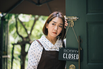 Asian beautiful woman sad mood with closed sign board hanging on the door of cafe because due to viral infection. Coronavirus and quarantine concept. go out of business