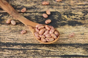 Spoon of dried pinto beans on wooden background
