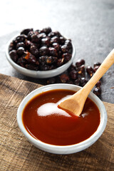 Homemade rosehip marmalade in ceramic bowl with dried rose hip fruits on wooden board.