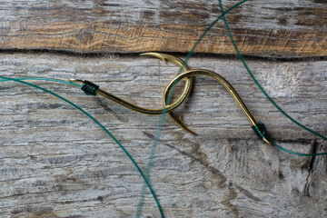 Two fishing hooks tied with fishing line on a wooden background.