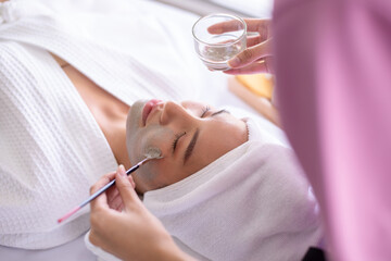 Therapist brush facial clay treatmetn on client face