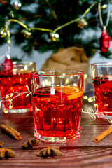 Close-up of three glasses of hot mulled red wine, on a wooden table with a Christmas tree in the background. Typical Christmas drink. Homemade Christmas concept. Vertical photography