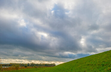 The edge of a lake in autumn colors under a cloudy sky at fall, Almere, Flevoland, The Netherlands, October 26, 2020