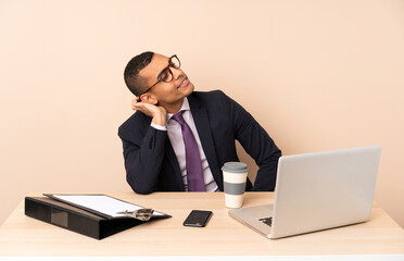 Young business man in his office with a laptop and other documents thinking an idea