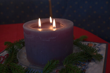 big purple lighted candle with three flames