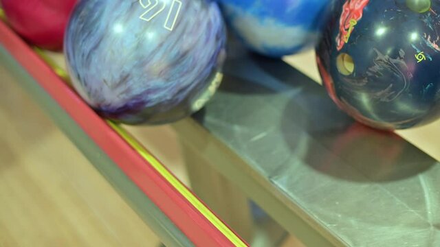The man takes the bowling ball in his hand. Close-up