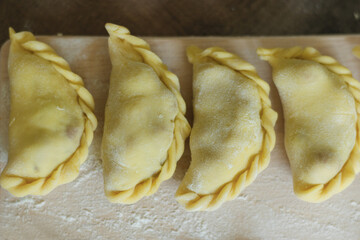 Dumplings with different fillings on a floured board. Homemade food close-up