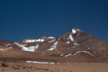 Alpine landscape. High in the Andes mountain range. Beautiful view of the arid brown mountains and desert under a deep blue sky.