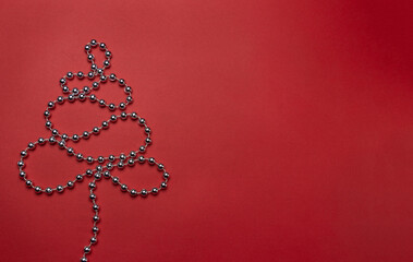 Christmas tree made of garland on red background, christmas decoration. New year's banner layout, top view with copy space