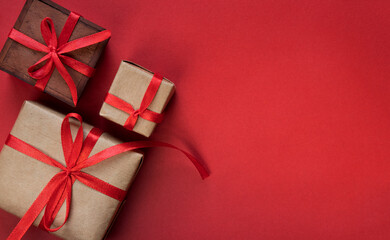 Gift boxes tied with red ribbons on red background, christmas decoration, presents packing with copy space