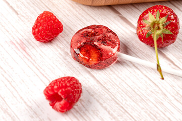 Homemade lollipops made from natural dehydrated strawberries and raspberries on a white wooden background. Healthy vegan vegetarian food with no sweets.