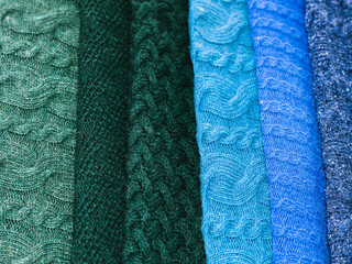 Knitted fabrics in blue and green colors. Warm fabrics with knitted patterns.