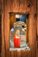 Candle in the jar in the wooden window.