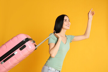 Beautiful woman with suitcase for summer trip on yellow background. Vacation travel