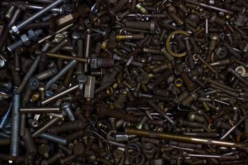 a mountain of nuts, bolts, screws, washers in the box, studs, rings, carving in dark colors, industrial in the garage, metal and bronze