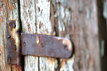 Rusty metallic hinge on a old wooden door with a peeled blue paint abstract background.