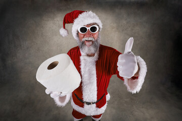 Santa Claus holding a roll of toilet paper and giving the thumbs up sign during pandemic