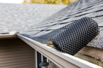 Roll of plastic mesh guard over gutter on a roof to keep it free of leaves and debris