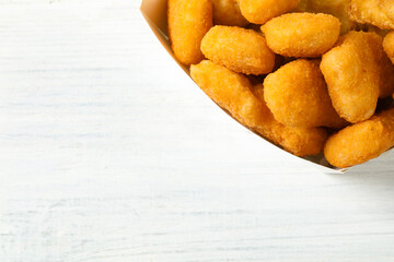 Tasty fried chicken nuggets on white wooden table, top view. Space for text