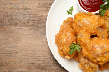 Tasty deep fried chicken pieces served on wooden table, top view. Space for text